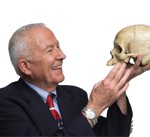 A photo of a man smiling and holding as skull