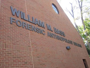 External view of a brick wall with the name William M. Bass Forensic Anthropology Building in gray letters on the side.